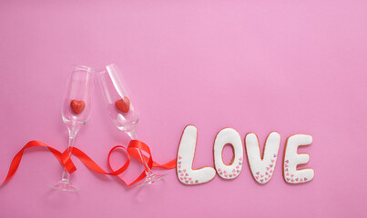 A glasses with hearts inside them, wrapped with a red ribbon in the shape of a heart. Gingerbread the inscription Love.