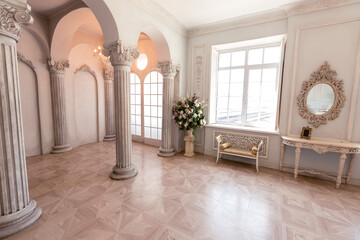 Fototapeta na wymiar Luxurious light interior of the living room in the baroque style as in a royal castle with old stylish vintage furniture, columns, stucco on the walls