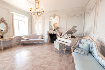 Luxurious light interior of the living room in the baroque style as in a royal castle with old stylish vintage furniture, columns, stucco on the walls