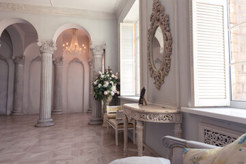 Luxurious light interior of the living room in the baroque style as in a royal castle with old stylish vintage furniture, columns, stucco on the walls