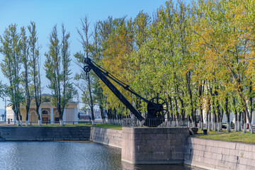 Old mechanical harbor crane of the XIX century on the shore of an Italian pond on a sunny autumn day in Kronstadt, Russia