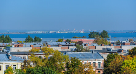Fototapeta na wymiar Rooftop Kronstadt view from belltower of Naval Cathedral of Saint Nicholas in golden autumn day with dam on background