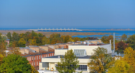Fototapeta na wymiar Rooftop Kronstadt view from belltower of Naval Cathedral of Saint Nicholas in golden autumn day with dam on background