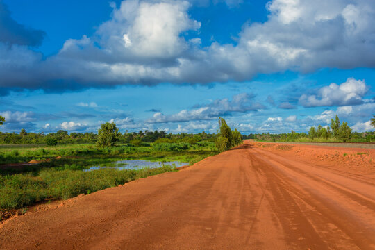 Sunset view of a typical red soils unpaved rough countryside road in Guinea, West Africa.