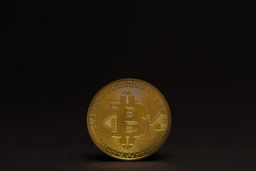 single golden shiny valuable bitcoin standing on a black background middle bottom