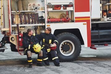 Male and female firefighters in protective uniform is outdoors together