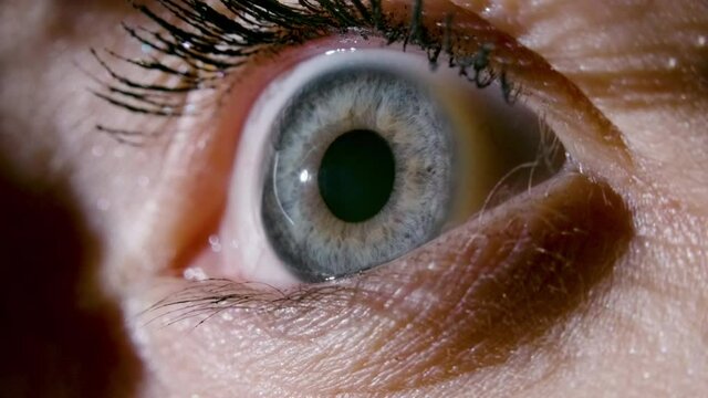 Close-up video of female blue eye with dilating pupil
