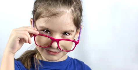 Poster Gezondheidszorg, oogbolcontrole, duidelijk visieconcept. Close-up portret van charmant schoolmeisje in rode en paarse bril © Albert Ziganshin