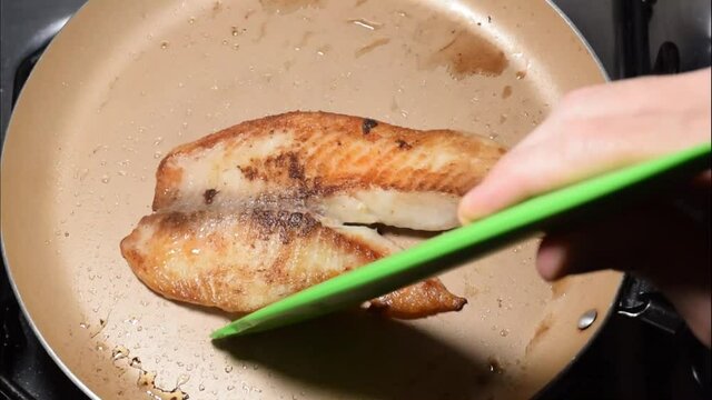 Tilapia fillet (Saint Peter) being fried in butter. Stirring the fish with a spatula.