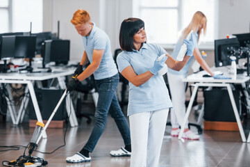Fototapeta premium Group of workers clean modern office together at daytime