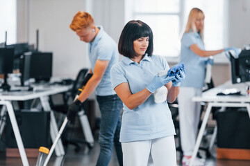 Cleans floor. Group of workers clean modern office together at daytime