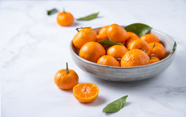 Sweet  tangerines in a ceramic  bowl on a white marble  background