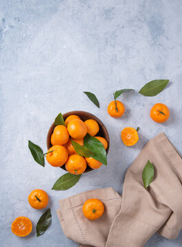 sweet and juicy tangerines in a wooden bowl and with linen napkin on a blue background © Ольга Кучкина