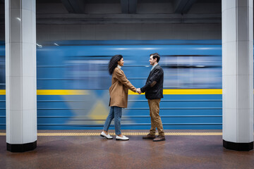 Fototapeta premium long exposure of interactional couple holding hands while standing near wagon in subway