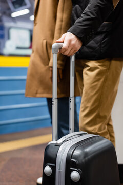 cropped view of couple standing on platform of subway with luggage