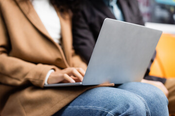 partial view of african american woman using laptop near man in subway