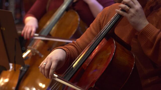 Symphony orchestra violin. Female cello player playing violoncello. Close up of woman hand playing cello. Cello player playing cello bow. Orchestra musicians instruments