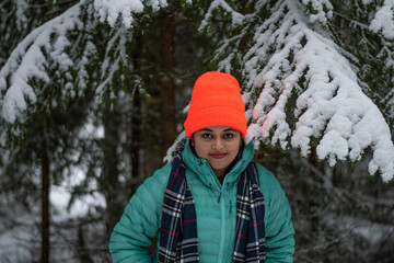 A beautiful caucasian young woman in a winter wonderland enjoying the snow fashion photoshoot wearing colourful jacket and red cap