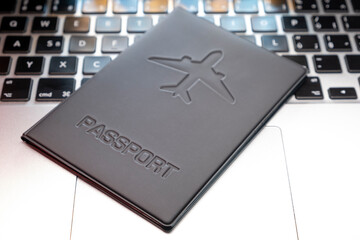 a passport over a laptop On Computer Keyboard . Planning a trip, buying tickets online. Blurred background
