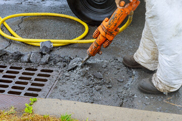 Jackhammer with a pneumatic drill perforating the asphalt of an urban road being renovated on street construction