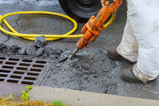 Jackhammer with a pneumatic drill perforating the asphalt of an urban road being renovated on street construction