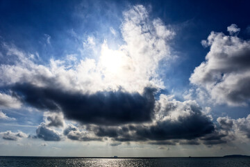 Obraz premium Bright sunlight over sea, beautiful shine sun beam in sky. Cloud sky with sun ray over the sea.