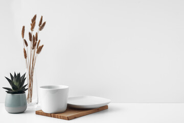 White cup and saucer on a wooden board, white background. Eco-materials and design. Copy space, mock up.