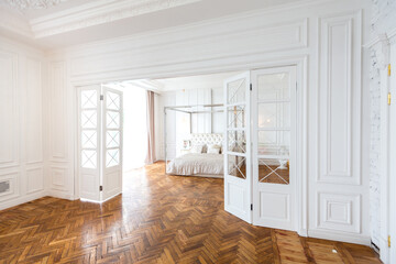 modern interior of a luxurious large bright bedroom. white stucco walls and a large four-poster bed...