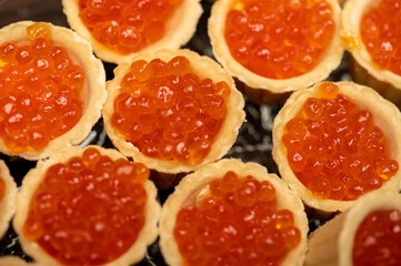 Tartlets with salmon caviar on a platter. Close-up, selective focus.