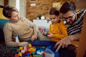 Happy family playing with toy blocks on the floor at home.