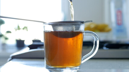 Image with Making a Hot and Aromatic Tea Using a Strainer and Natural Tea Leafs