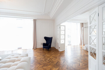 modern interior of a luxurious large bright two-room apartment. white walls, luxurious expensive furniture, parquet flooring and white interior doors