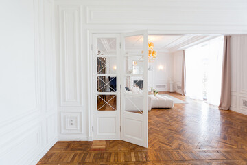 modern interior of a luxurious large bright two-room apartment. white walls, luxurious expensive furniture, parquet flooring and white interior doors