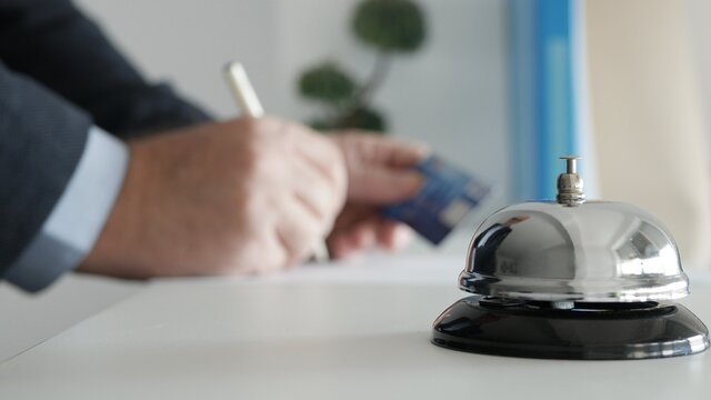 Tourist in the Reception of a Hotel Fills in Form with Personal Data