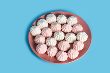 Sugar protein dessert in pastel colors in a pink plate on blue background. The view from the top