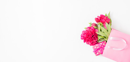 Valentines day composition with red peonies in a pink paper bag and gift box on a white background