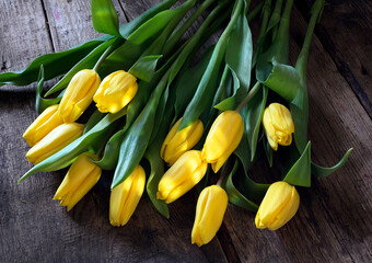 A bouquet of yellow tulips on a wooden table.