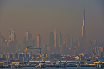 Obraz premium Blick in den Hafen von Dubai im Morgendunst mit goldenem Licht und der Skyline im Hintergrund