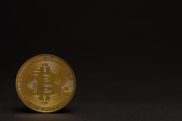 single golden shiny valuable bitcoin standing on a black background left bottom