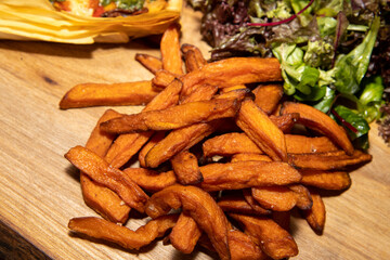 A pile of rustic fries or chips on a wooden board.