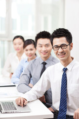 Executives sitting at conference table focus on woman in foreground 