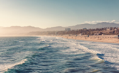 View of Santa Monica Beach and Los Angeles in afternoon sun. Aerial view from above the pacific ocean water.