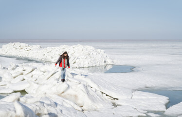 Young adult woman outdoors travelling with backpack in icy landscape