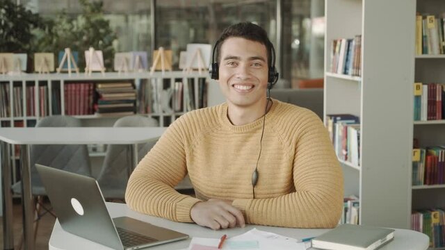Young smilling man with hadset working in call centre, looking to camera