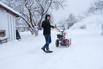 young man clearing snow in his backyard with wheeled snow blower