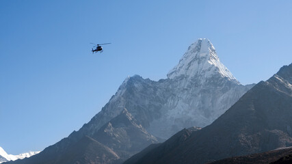 Fototapeta premium Ama Dablam peak with a rescue helicopter flying nearby, Nepal