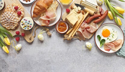 Easter Breakfast food table. Festive brunch set, meal variety with fried egg, croissant sandwich,...