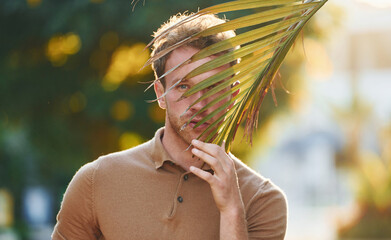 Bright sunshine. Young man is outdoors at sunny daytime. Concept of vacation