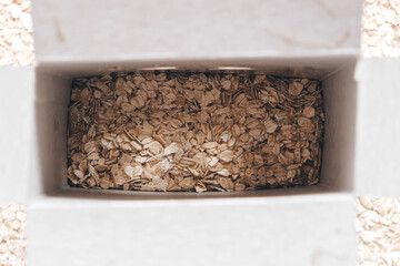 Obraz premium Dry oatmeal in a paper box. Top view. Copy, empty space for text