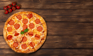 Tasty fresh pepperoni pizza and ingredients tomatoes basil on wooden background. Top view of pepperoni pizza. Flat lay. With copy space for text. Banner